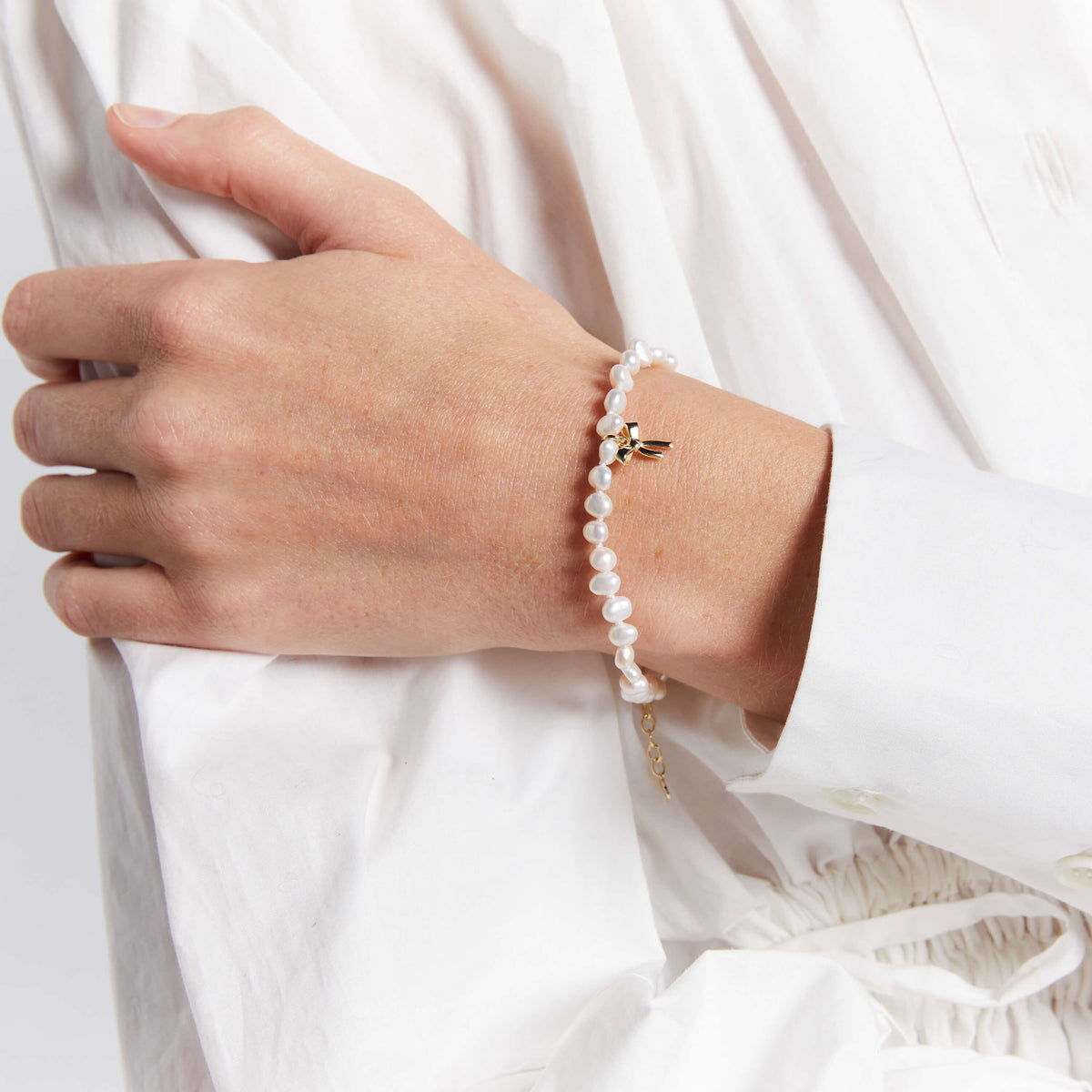 Model wearing Karen Walker petite bow pearl bracelet