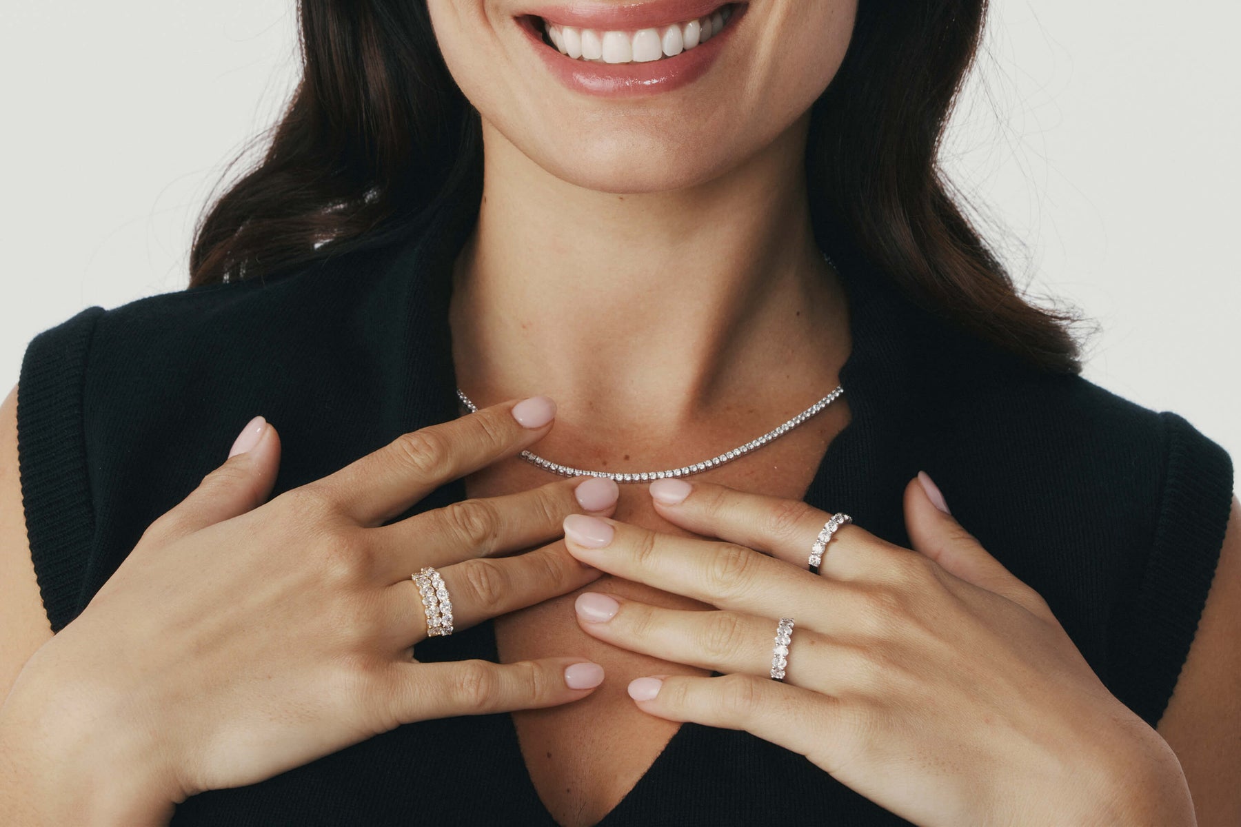 Woman wearing multiple rings on her fingers with a neutral background