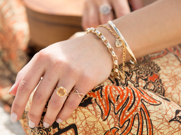 Model wearing a stack of gold bracelets