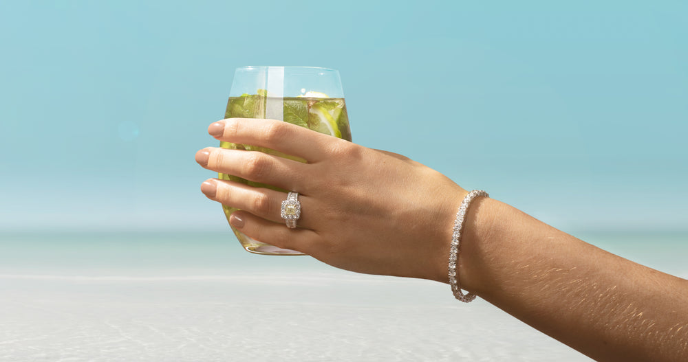 Model wearing diamond ring and bracelet holding a drink