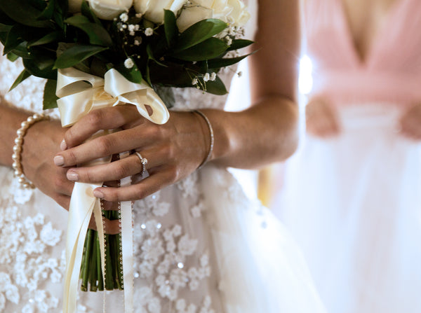 Bride holding flowers wearing diamond rings and pearl bracelet