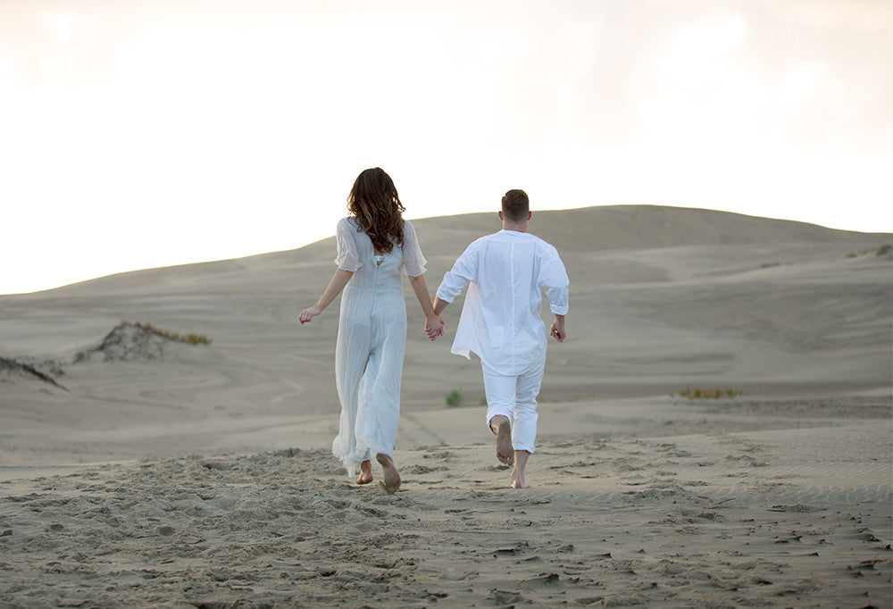 Couple running across sand dunes