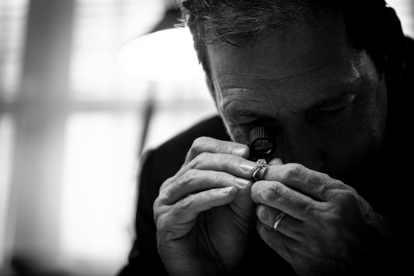 Gemmologist looking at diamond ring through a loupe