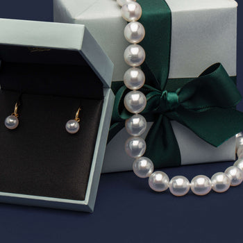 Pearl Strand and Pearl Cosy Earrings on navy blue background with wrapped Walker & Hall gift boxes