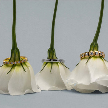 Three white roses upside down with diamond bands on the stems