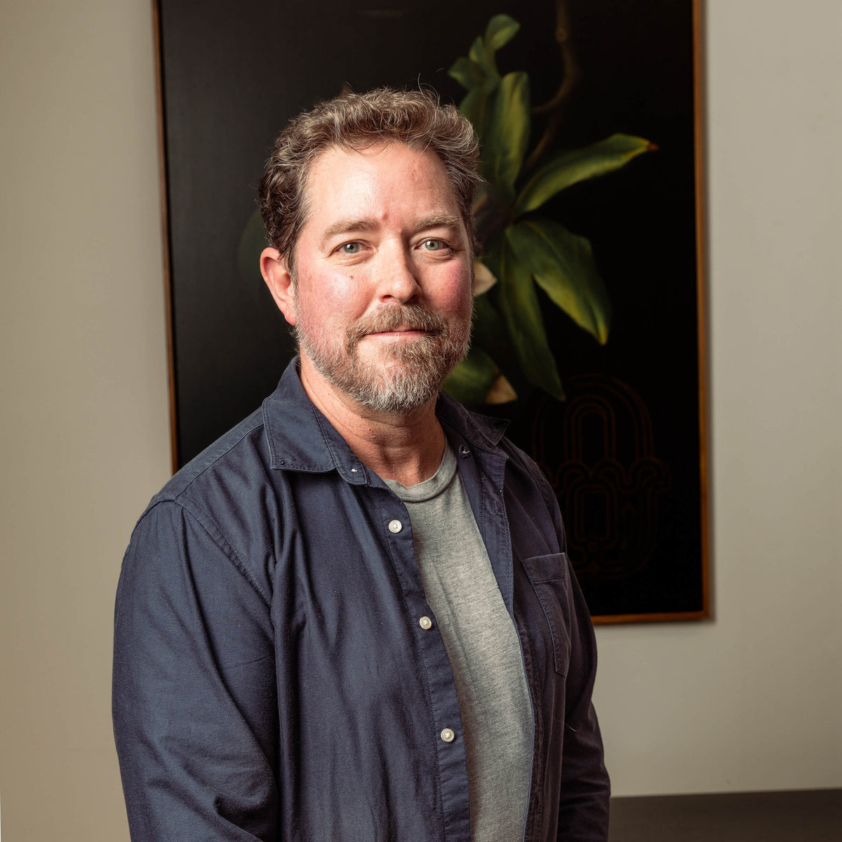Artist Tom Wilson standing in front of one of his paintings