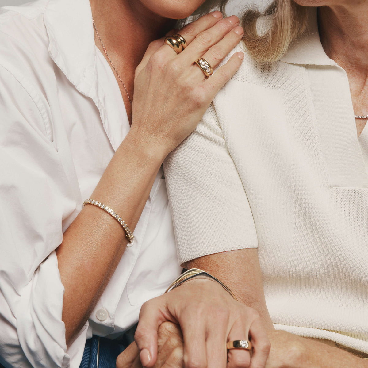 Close up of mother and daughter holding hands and daughter resting her hand on her mother's shoulder