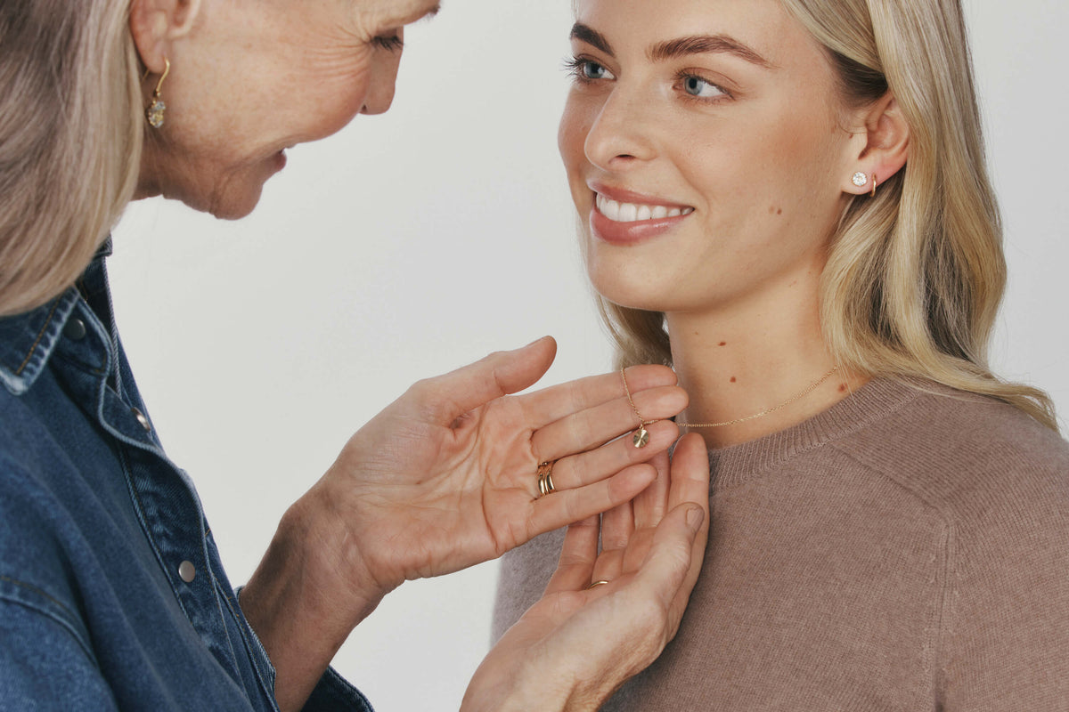 Grandmother admiring necklace on granddaughter's neck