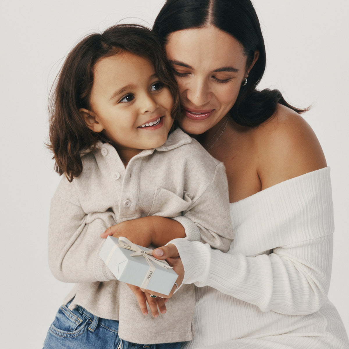 Woman and child holding a gift box against a plain background