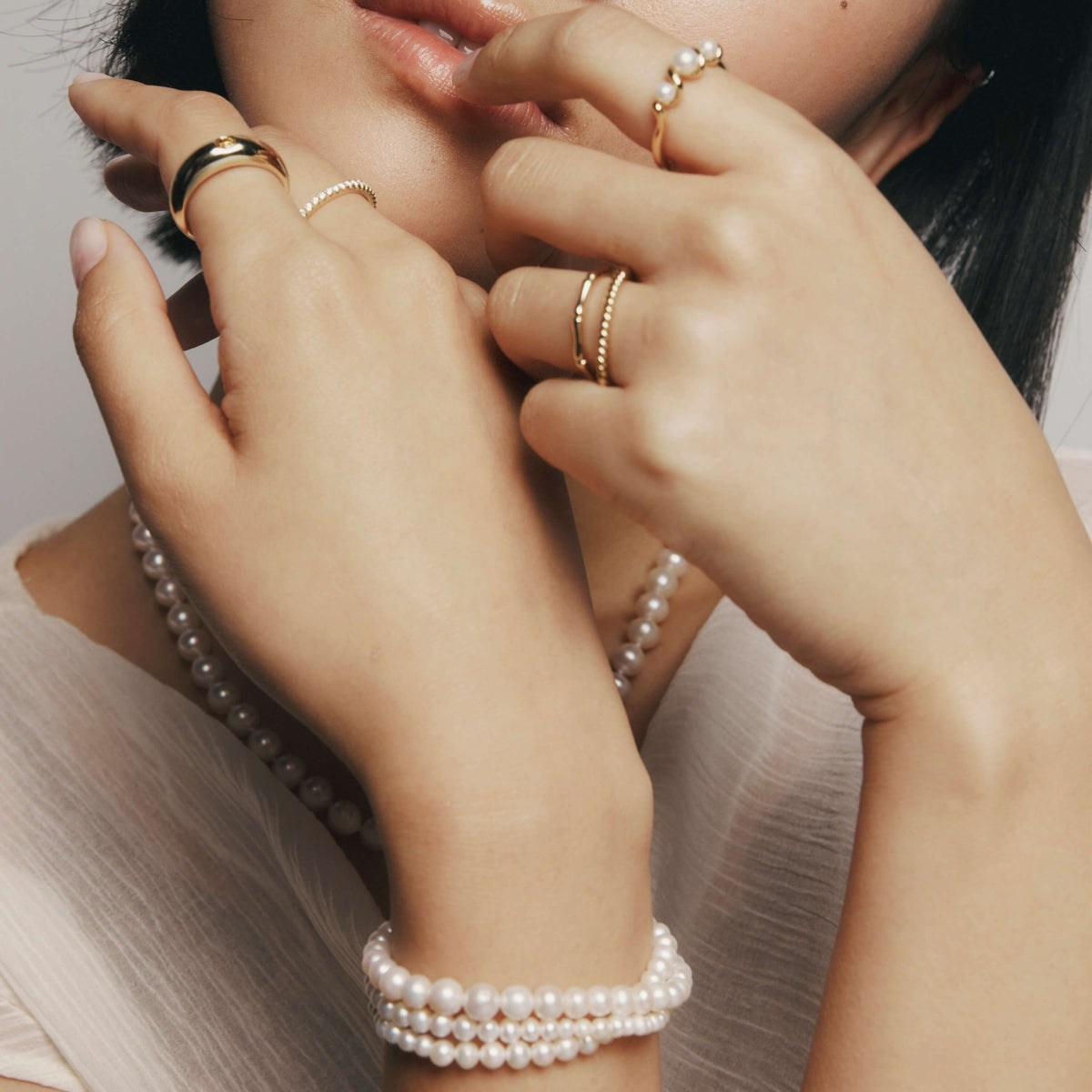 Model wearing pearl bracelet and gold and pearl ring