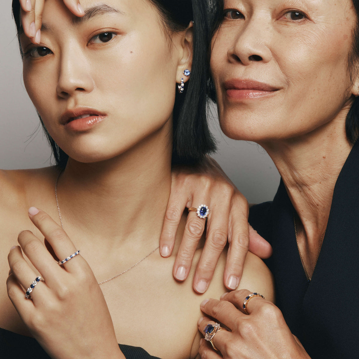 Two models wearing sapphire and diamond rings and earrings