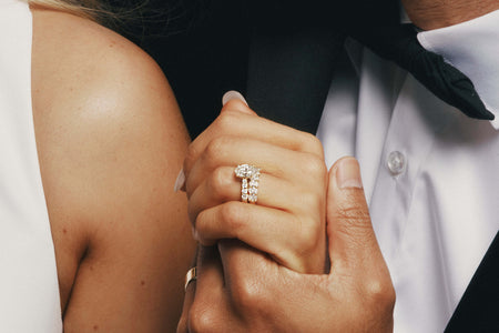 Bride and groom holding hands, bride wearing oval cut diamond ring