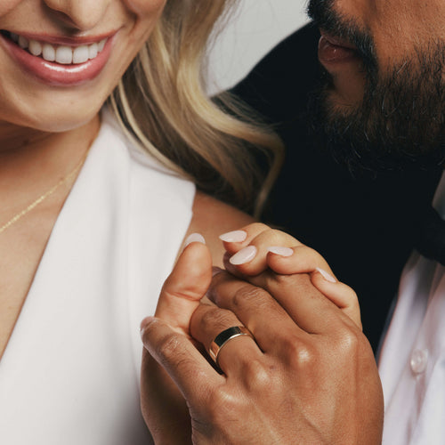 Bride and groom holding hands with groom wearing a yellow gold wedding band