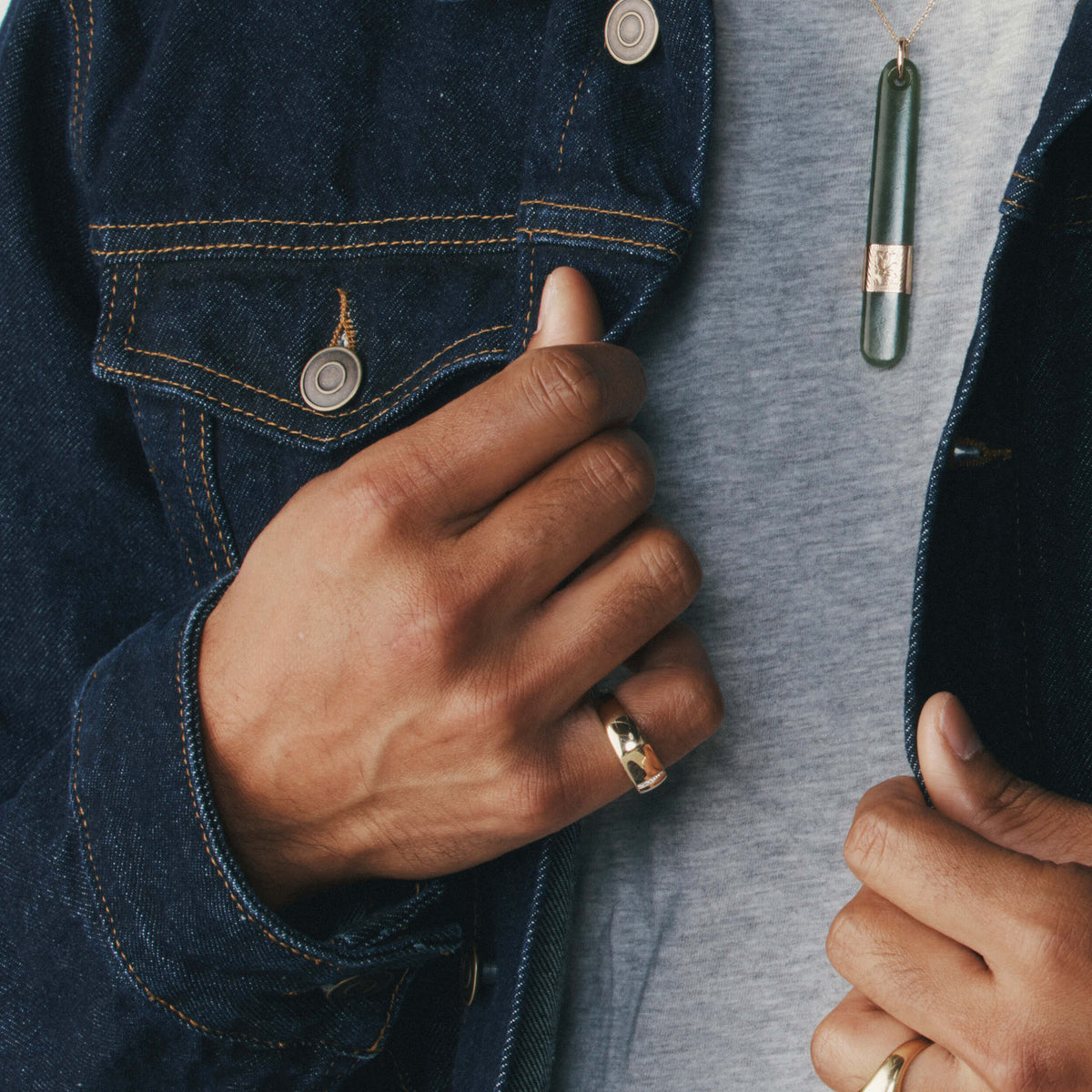 Close up of male model wearing denim jacket and yellow gold signet ring