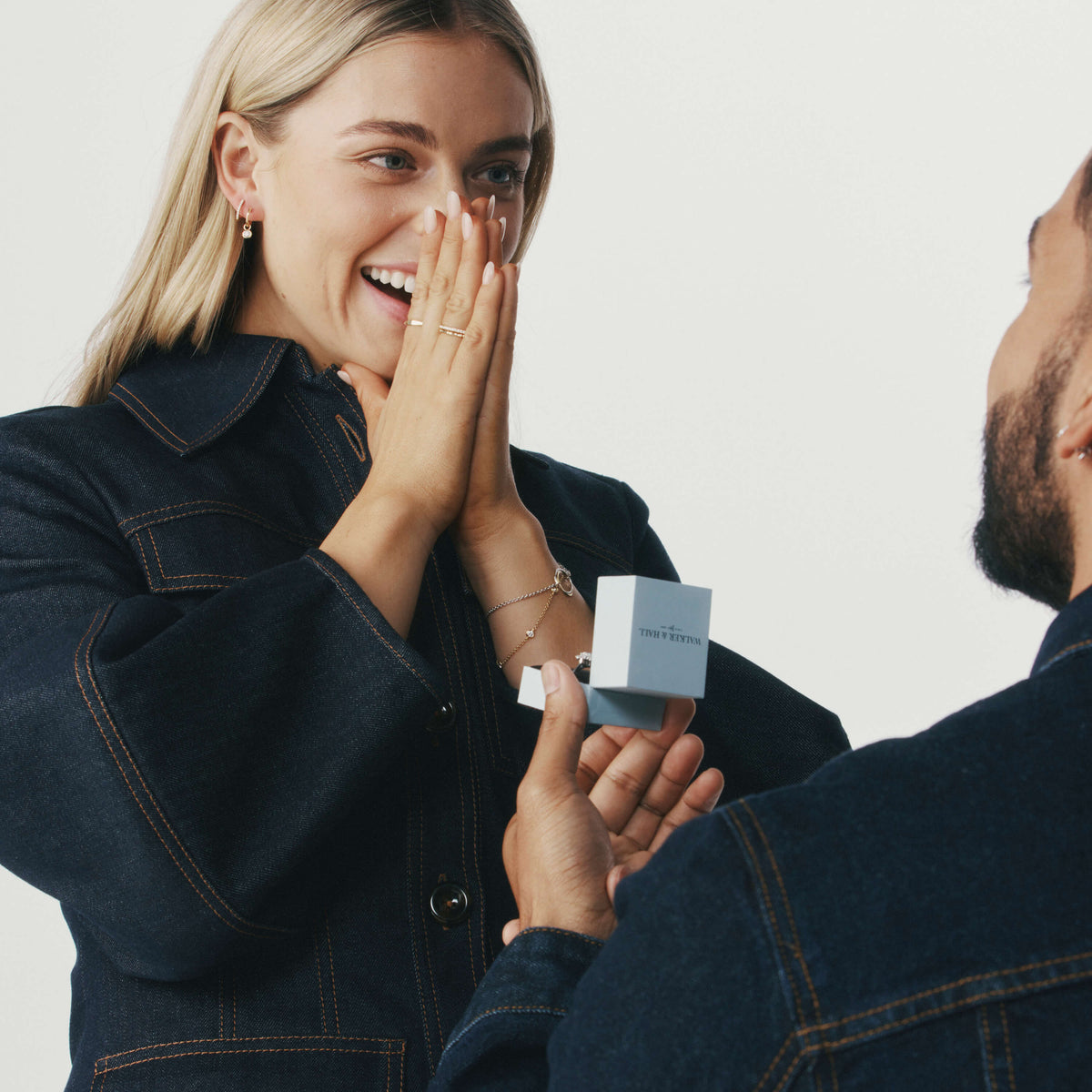Man on one knee proposing to his partner with a Walker & Hall ring box