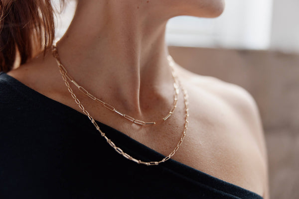 Model wearing recycled gold chain necklaces