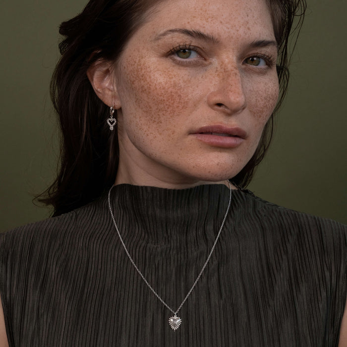 Model wearing Zoe & Morgan earrings and necklace against a green background
